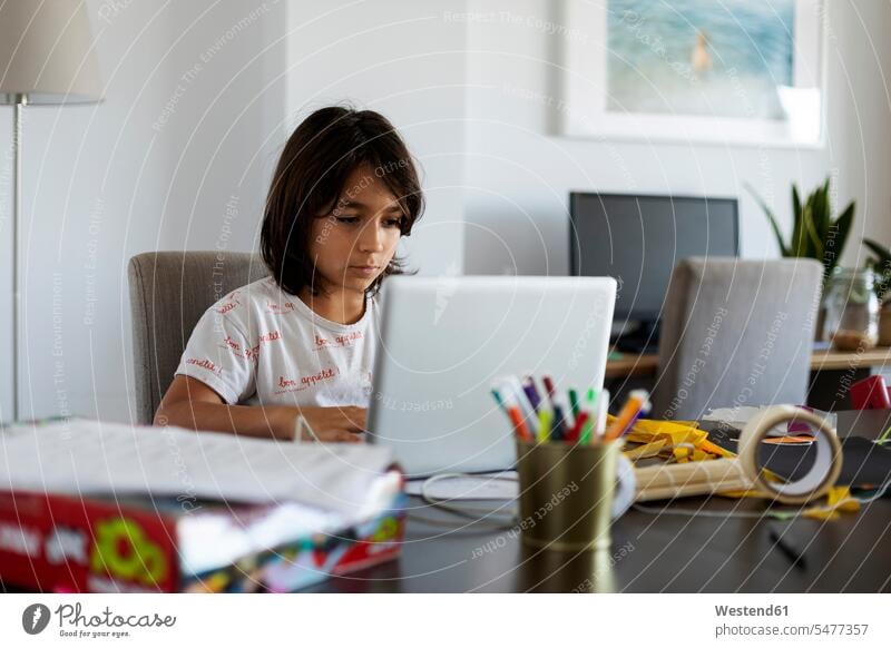 Porträt eines Jungen, der mit einem Laptop am Tisch im Wohnzimmer sitzt Tische Stifte Rechner Laptops Notebook Notebooks daheim zu Hause Muße Technik