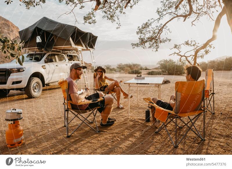 Namibia, Freunde zelten bei Spitzkoppe Berg Berge sitzen sitzend sitzt Camping Campen Freundschaft Kameradschaft Landschaft Landschaften Autoreise Reisende
