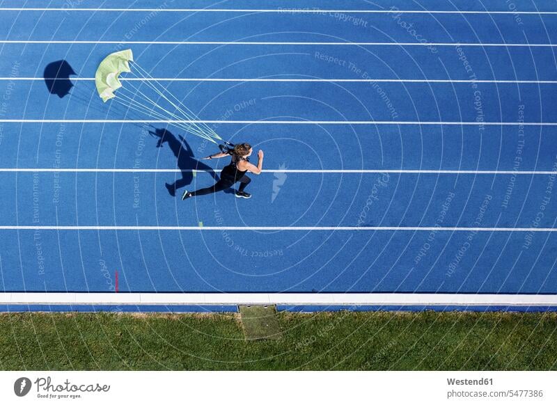 Draufsicht einer Läuferin mit Fallschirm auf der Tartanbahn Schirme rennen Farben Farbtoene Farbton Farbtöne blaue blauer blaues geschwind Schnelligkeit