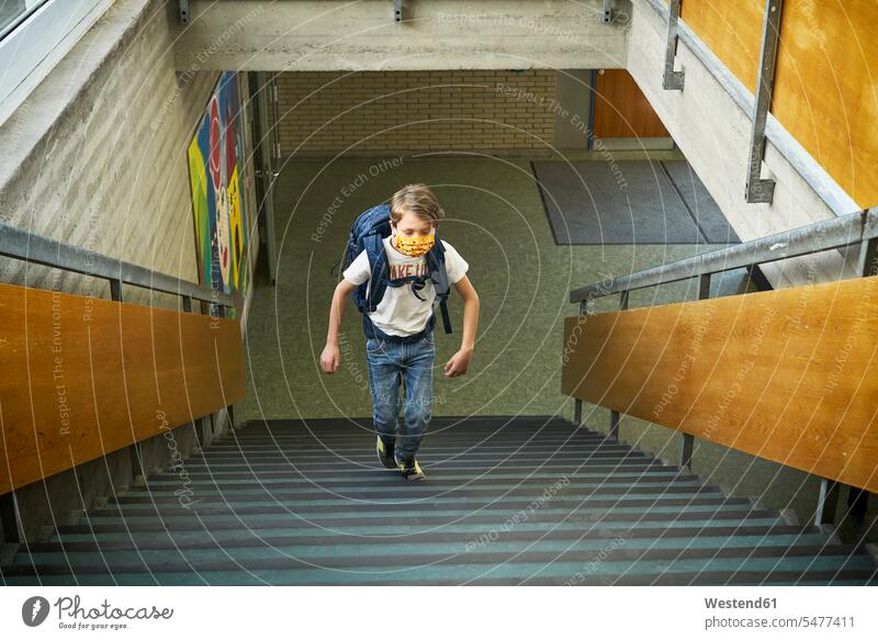 Junge mit Maske in der Schule beim Treppensteigen Ausbildung Schueler Schulkinder Schüler Rucksäcke T-Shirts gehend geht Gesund geschützt schützen Absicherung