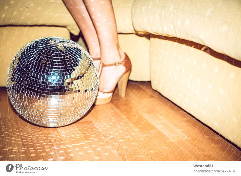 Junge Frau in Stöckelschuhen steht bei der Disco-Kugel auf dem Boden in Party Farbaufnahme Farbe Farbfoto Farbphoto Innenaufnahme Innenaufnahmen innen drinnen