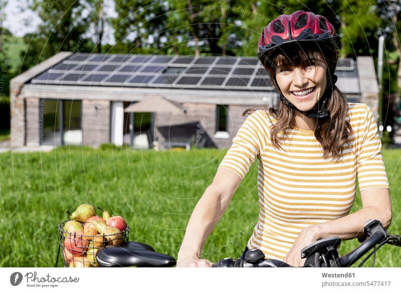 Porträt einer glücklichen Frau mit Fahrrad und Bio-Obst auf einer Wiese vor einem Haus Leute Menschen People Person Personen Europäisch Kaukasier kaukasisch 1