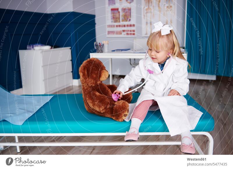 Mädchen mit Stethoskop untersucht Teddy in der medizinischen Praxis Teddies untersuchen prüfen Arztpraxis Arztpraxen Stethoskope weiblich Teddybär Teddybaer