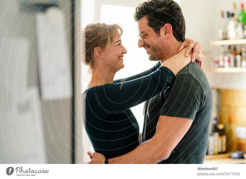 Glückliches Paar umarmt sich zu Hause in der Küche Leute Menschen People Person Personen erwachsen 30 - 40 Jahre 30 bis 40 30 bis 40 Jahre 30-40 35 - 40 Jahre