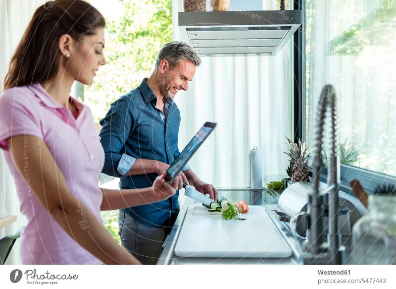 Ehepaar in der Küche beim Kochen zu Hause und bei der Verwendung einer Tablette Tablet Computer Tablet-PC Tablet PC iPad Tablet-Computer Paar Pärchen Paare
