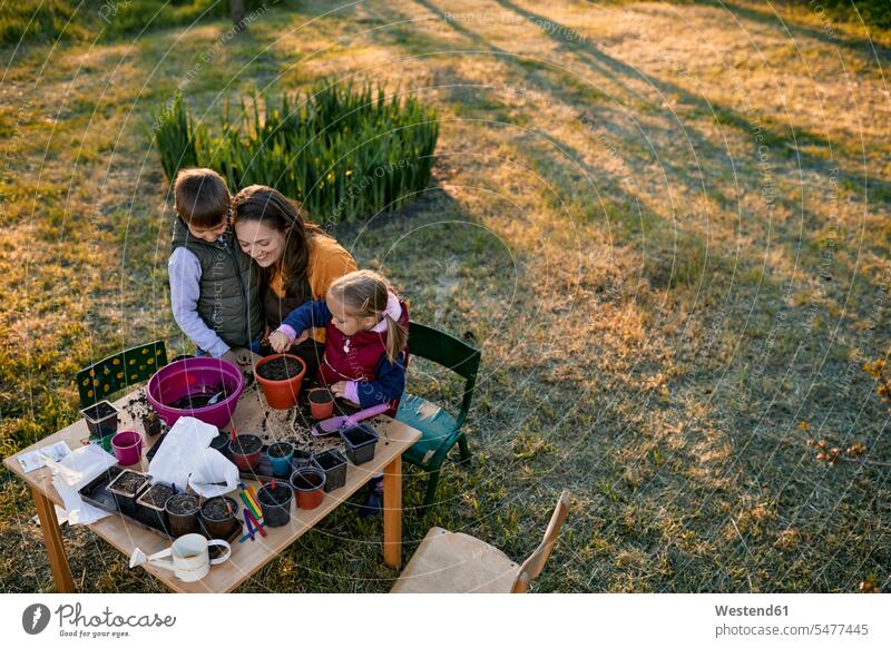 Mutter mit zwei Kindern bei der Gartenarbeit Blumentoepfe Blumentöpfe Tische Jahreszeiten Frühjahr Lenz freuen geniessen Genuss Glück glücklich sein
