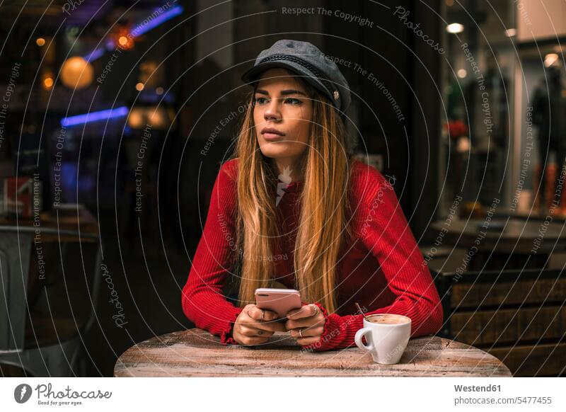 Porträt der nachdenklichen jungen Frau mit Smartphone sitzt auf der Terrasse eines Cafés Coffee Shop Coffee Shops iPhone Smartphones sitzen sitzend weiblich