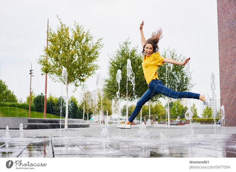 Glückliche junge Frau springt in die Luft Luftsprung Luftsprünge einen Luftsprung machen Luftspruenge weiblich Frauen glücklich glücklich sein glücklichsein