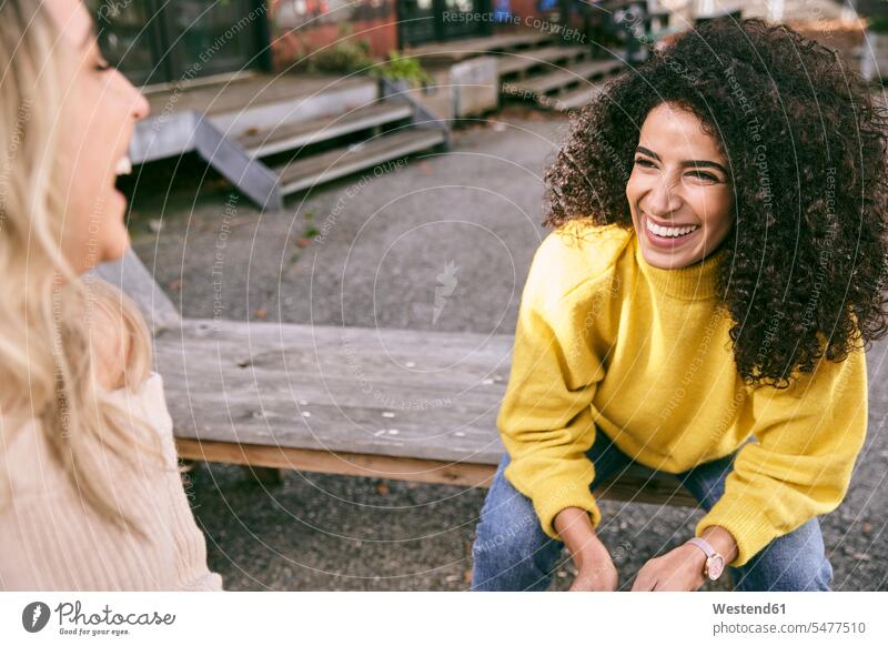 Fröhliche Freundinnen unterhalten sich beim Sitzen im Freien Farbaufnahme Farbe Farbfoto Farbphoto Deutschland Freizeitbeschäftigung Muße Zeit Zeit haben