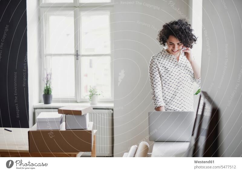 Lächelnde junge Frau am Telefon mit Laptop im Home-Office Job Berufe Berufstätigkeit Beschäftigung Jobs geschäftlich Geschäftsleben Geschäftswelt