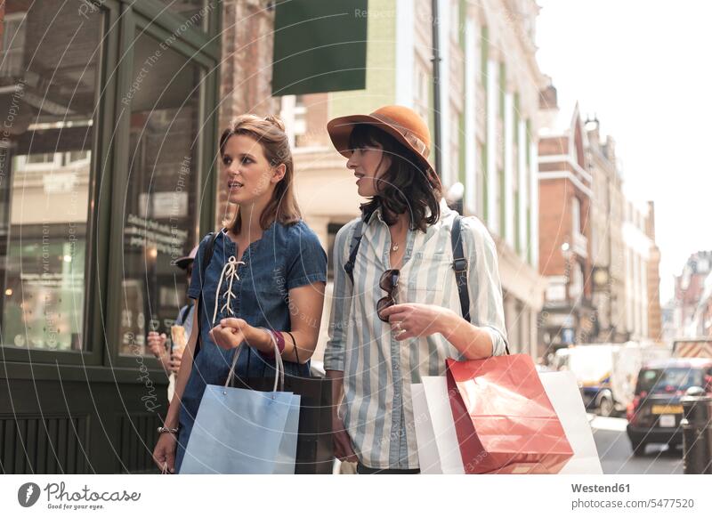 Schöne Freundinnen unterhalten sich beim Spaziergang mit Einkaufstaschen in der Stadt Farbaufnahme Farbe Farbfoto Farbphoto Außenaufnahme außen draußen