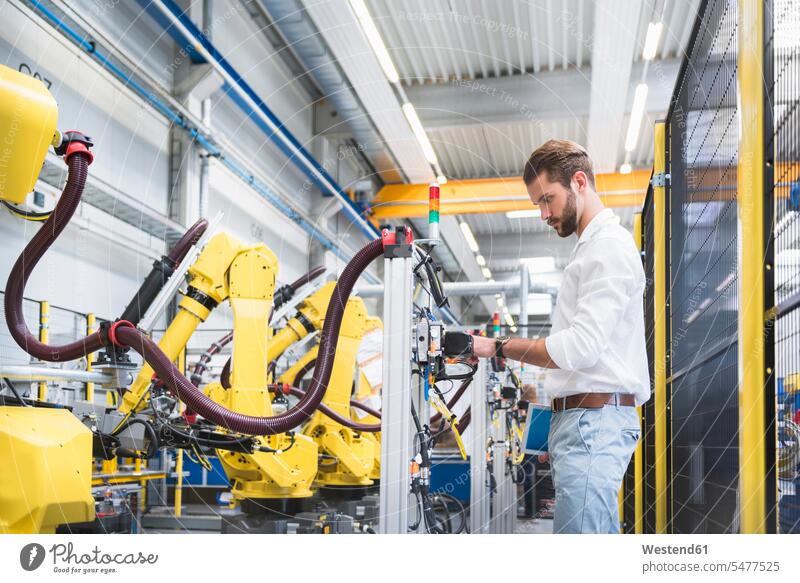 Seitenansicht eines selbstbewussten Robotik-Experten, der Maschinen in einer Fabrik untersucht Farbaufnahme Farbe Farbfoto Farbphoto Deutschland Innenaufnahme