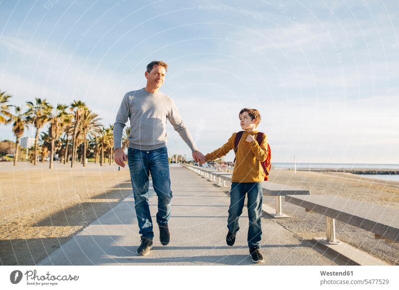 Vater und Sohn spazieren an der Strandpromenade Beach Straende Strände Beaches gehen gehend geht Söhne Papas Väter Vati Vatis Papis Promenade Promenaden Kind