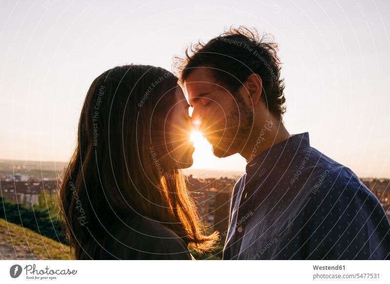 Mann und Frau küssen sich, während sie gegen den klaren Himmel stehen Farbaufnahme Farbe Farbfoto Farbphoto Außenaufnahme außen draußen im Freien