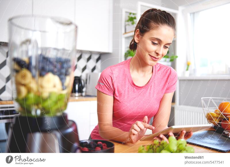 Porträt einer lächelnden jungen Frau mit Tablette in der Küche weiblich Frauen Tablet Computer Tablet-PC Tablet PC iPad Tablet-Computer Küchen Portrait Porträts
