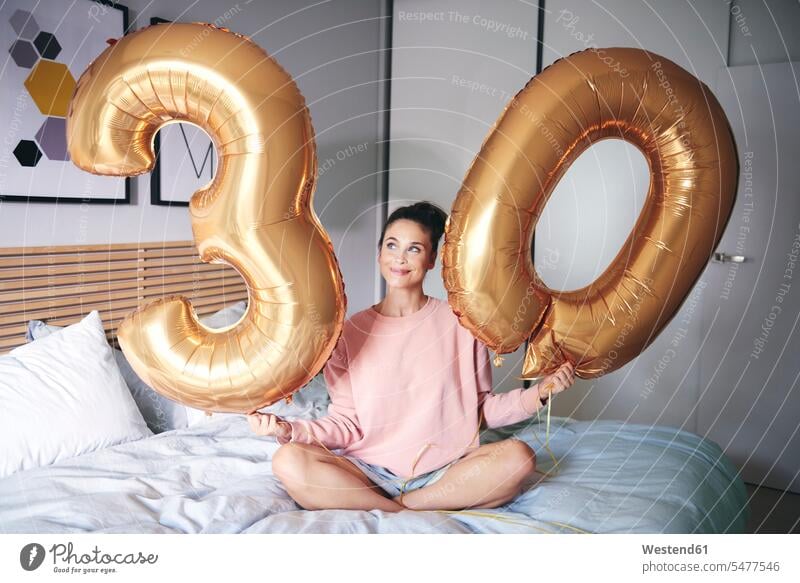 Glückliche Frau hält goldene Luftballons am Geburtstagsmorgen weiblich Frauen glücklich glücklich sein glücklichsein lächeln Bett Betten Allein alleine einzeln