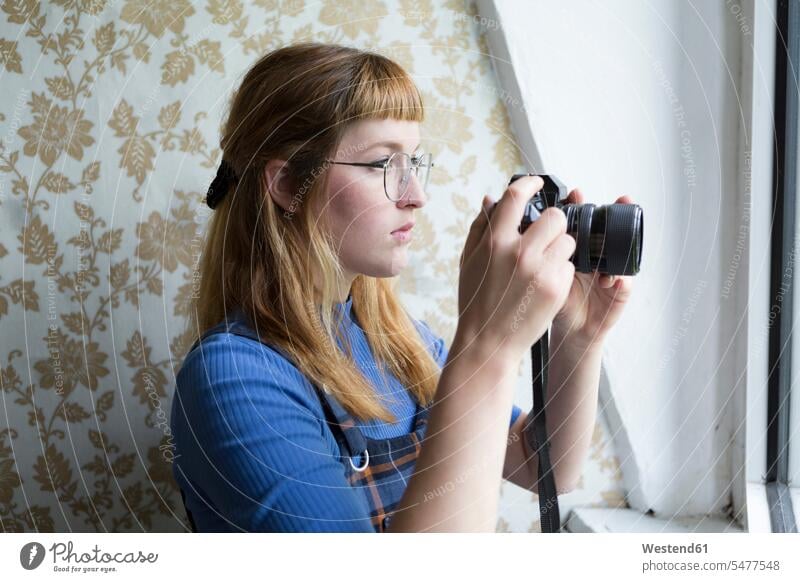 Studentin mit Kamera Deutschland Nasenring aus dem Fenster sehen durchs Fenster schauen aus dem Fenster schauen hinaussehen Wohnung wohnen Wohnungen Betrachtung