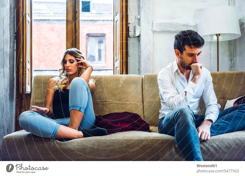 Paar sitzt auf Sofa auseinander und ist wütend nach Streit Couch Couches Liege Sofas sitzend gelangweilt langweilig aergern missmutig muerrisch mürrisch