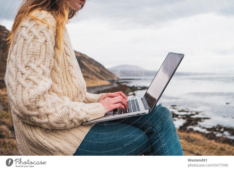 Island, Frau mit Laptop an der Küste Kueste Kuesten Küsten Republik Island Notebook Laptops Notebooks weiblich Frauen Computer Rechner Erwachsener erwachsen