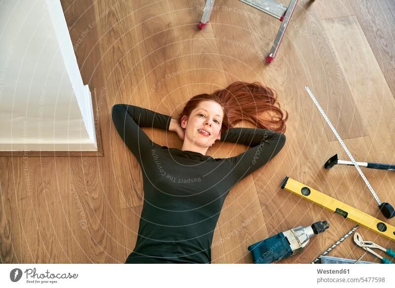 Rothaarige Frau liegt neben Werkzeugen auf dem Boden liegen liegend Fußboden Fußboeden Fussboeden Fussboden Fußböden Fussböden rothaarig rote Haare rothaarige