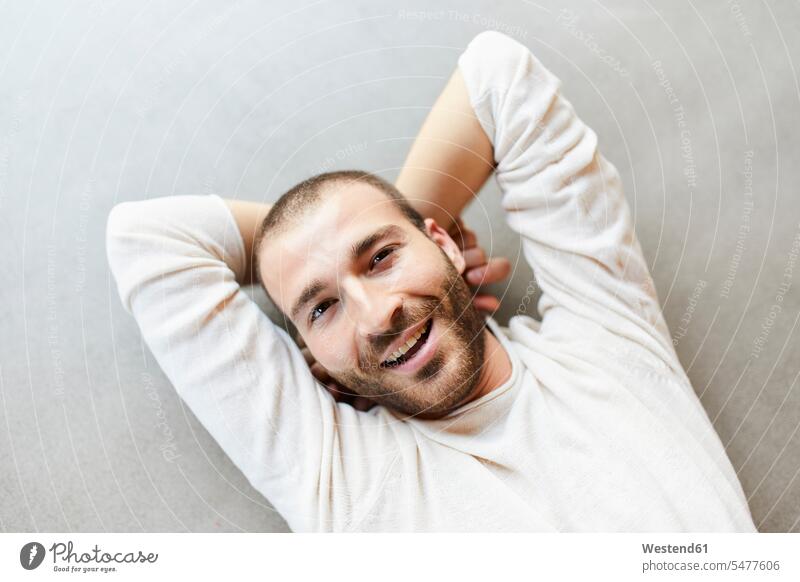 Porträt eines glücklichen jungen Mannes, der auf dem Boden liegt ausruhen Rast Erholung erholen Böden Boeden Freizeit Muße Spaß Spass Späße spassig Spässe