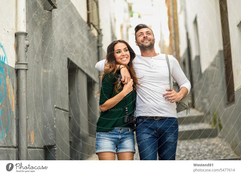 Glückliches Touristenpaar beim Spaziergang in der Stadt gehen gehend geht glücklich glücklich sein glücklichsein staedtisch städtisch Paar Pärchen Paare