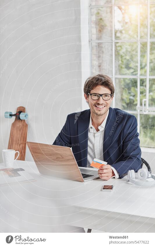 Porträt eines lächelnden Geschäftsmannes mit Laptop auf dem Schreibtisch mit Karte Notebook Laptops Notebooks Businessmann Businessmänner Geschäftsmänner halten