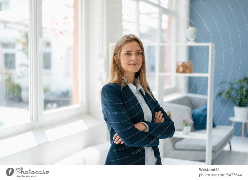 Porträt einer selbstbewussten jungen Geschäftsfrau, stehend im Büro Arme verschränkt Arme gekreuzt verschränkte Arme Zuversicht Zuversichtlich Selbstvertrauen