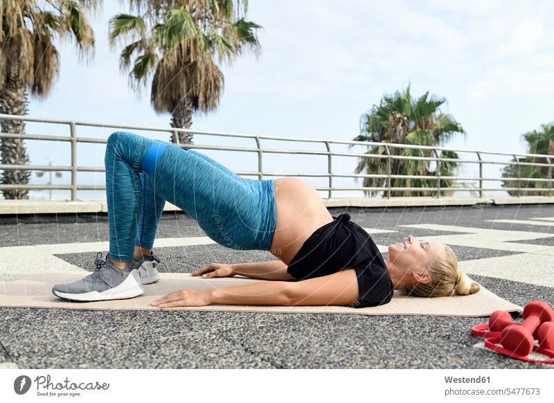 Schwangere Frau übt auf Gymnastikmatte im Freien üben ausüben Übung trainieren Gymnastikmatten Matte Matten weiblich Frauen schwanger schwangere Frau Sport