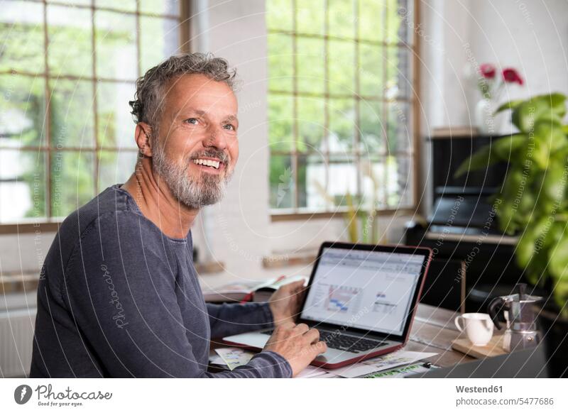 Reifer Mann arbeitet in seinem Heimbüro in einer Loft-Wohnung Home Office homeoffice zuhause zuhause arbeiten arbeiten von zuhause Laptop benutzen