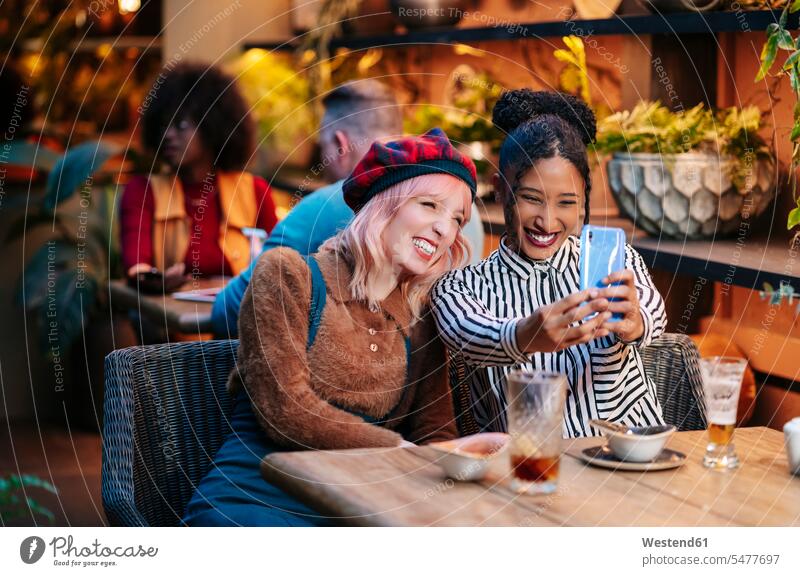 Zwei Freundinnen sitzen im Restaurant und machen Smartphone Selfies drinnen Innenaufnahmen Gastronomie Lokal Lokale Restaurants Speiselokal Speiselokale