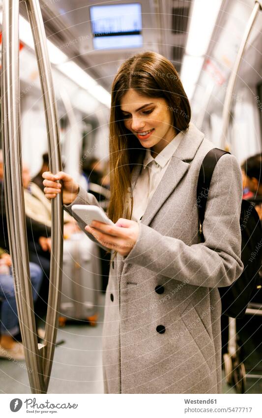 Spanien, Barcelona, junge Geschäftsfrau benutzt Handy in U-Bahn-Zug Ubahn U-Bahnen Untergrundbahnen Ubahnen Underground Subway Smartphone iPhone Smartphones