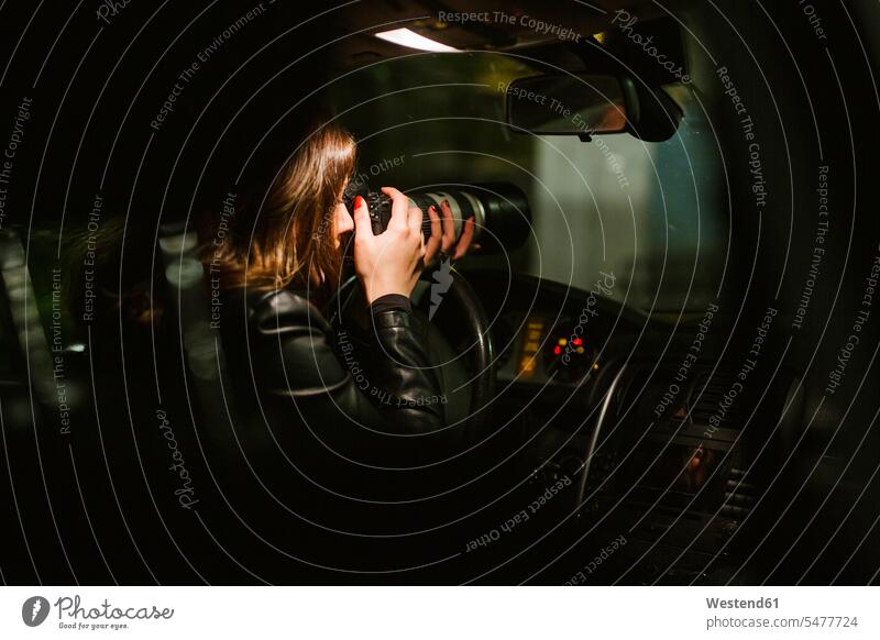 Junge Frau nimmt Bilder mit einer Kamera aus einem Auto in der Nacht Job Berufe Berufstätigkeit Beschäftigung Jobs Bildnis Fotos KFZ Verkehrsmittel Automobil