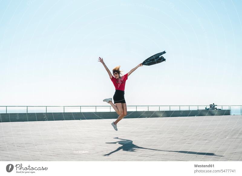 Modische junge Frau springt auf Uferpromenade Promenade Promenaden modisch springen hüpfen Uferpromenaden weiblich Frauen Sprung Spruenge Sprünge Erwachsener