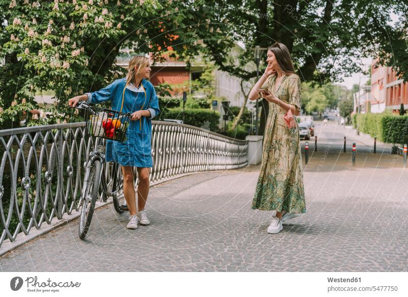 Zwei Frauen mit Fahrrad und Gesichtsmaske gehen auf einer Brücke Freunde Kameradschaft Freundin Raeder Räder Bike Bikes Fahrräder Rad gehend geht reden freuen
