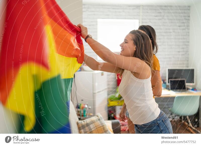 Lesbisches Paar hängt zu Hause Regenbogenfahne auf Fahnen Flaggen freuen Glück glücklich sein glücklichsein gefühlvoll Emotionen Empfindung Empfindungen fühlen