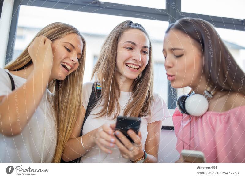 Glückliche Teenager-Mädchen benutzen Mobiltelefone in der Schule glücklich Handy Schüler Telefon Kommunikation Bildung Mensch chatten Südafrika Freundinnen