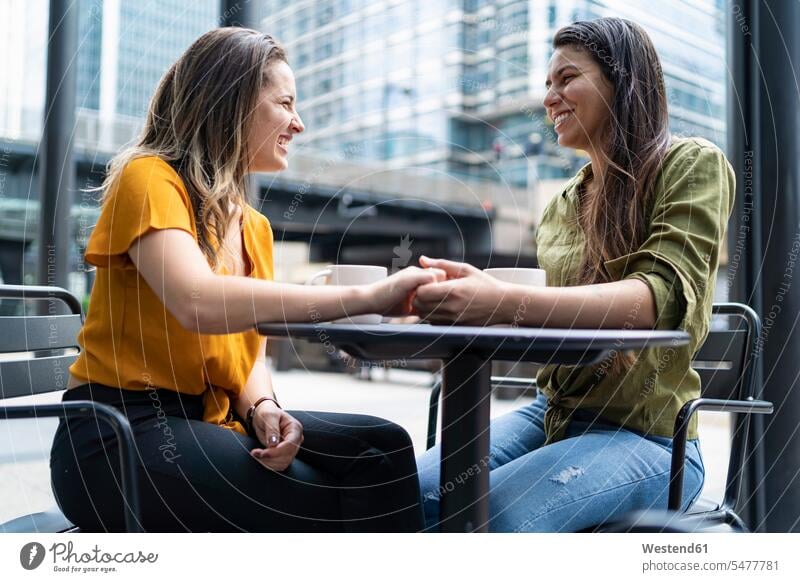 Glückliches lesbisches Paar in einem Straßencafé in der Stadt, London, Großbritannien sitzend sitzt reden entspannen relaxen entspanntheit relaxt freuen
