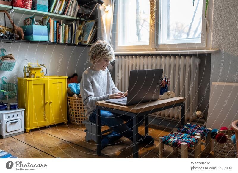 Junge benutzt Laptop in seinem Zimmer zu Hause Tische Rechner Laptops Notebook Notebooks sitzend sitzt allein daheim Muße Technik Technologien Lifestyles mobil