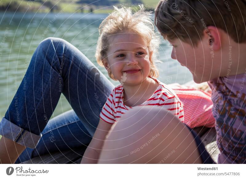 Österreich, Tirol, Walchsee, glückliche Geschwister lächeln sich am Seeufer an Schwester Schwestern Glück glücklich sein glücklichsein Familie Familien Seen