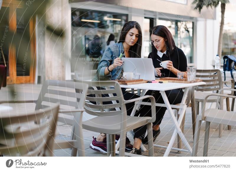 Zwei Freunde sitzen zusammen an einem Bürgersteig Café mit Laptop Business Geschäftsleben Geschäftswelt geschäftlich WLan Wireless Lan W-Lan Wifi