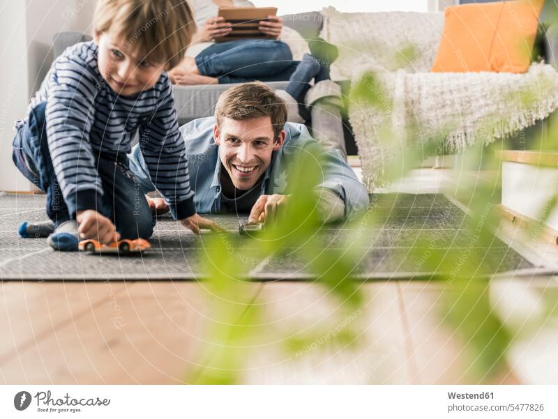 Vater und Sohn spielen mit Spielzeugautos, auf dem Boden liegend Auto Autos Teppiche freuen Glück glücklich sein glücklichsein zufrieden Muße Miteinander