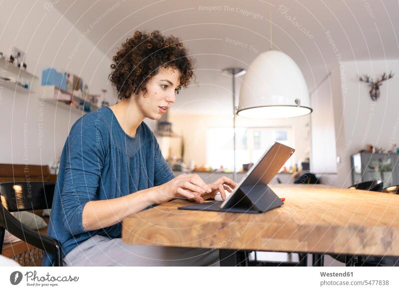 Junge Frau sitzt am Tisch und benutzt ein digitales Tablet benutzen benützen Tablet Computer Tablet-PC Tablet PC iPad Tablet-Computer sitzen sitzend Tische