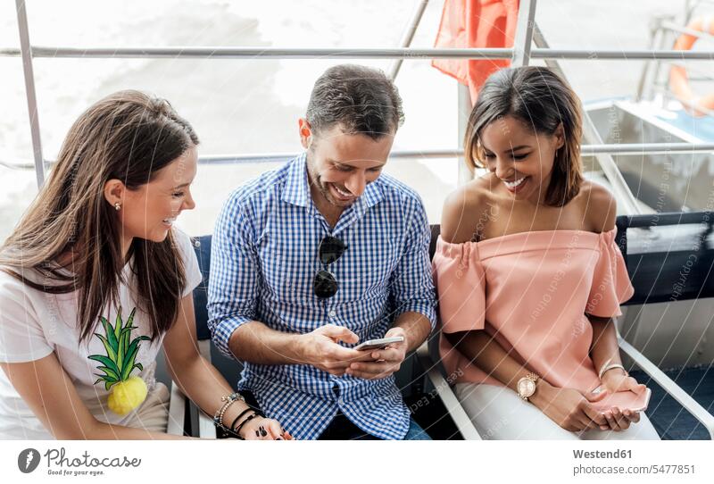 UK, London, glückliche Freunde mit Handy während der Fahrt mit dem Boot auf der Themse Mobiltelefon Handies Handys Mobiltelefone Glück glücklich sein
