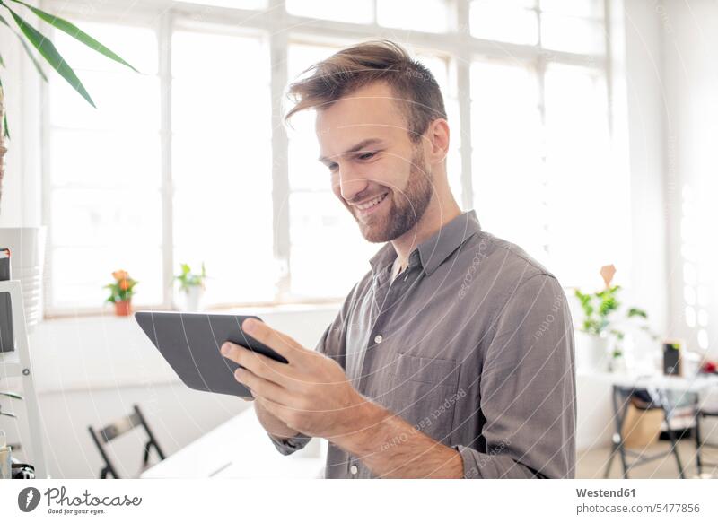 Lächelnder Mann mit Tablette im Büro Job Berufe Berufstätigkeit Beschäftigung Jobs geschäftlich Geschäftsleben Geschäftswelt Geschäftsperson Geschäftspersonen