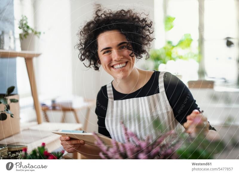 Porträt einer glücklichen jungen Frau mit Klemmbrett in einem kleinen Laden mit Pflanzen Leute Menschen People Person Personen Europäisch Kaukasier kaukasisch 1