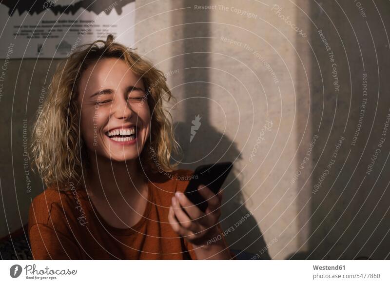 Porträt einer lachenden jungen Frau mit Handy Telekommunikation Handies Handys Mobiltelefon Mobiltelefone freuen Frohsinn Fröhlichkeit Heiterkeit Glück