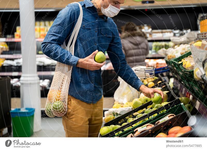 Mittelteil eines Mannes mit Gesichtsmaske beim Kauf von Granny-Smith-Äpfeln im Supermarkt Farbaufnahme Farbe Farbfoto Farbphoto Spanien Freizeitbeschäftigung