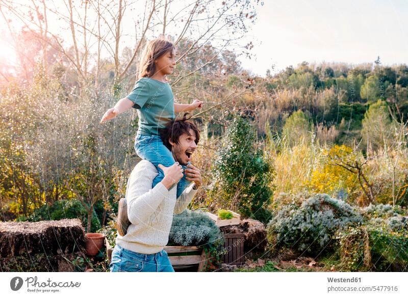 Vater trägt Sohn Huckepack in einem Garten auf dem Lande spielen Gärten Gaerten albern herumalbern Albernheit tragen transportieren Unbeschwert Sorglos Söhne