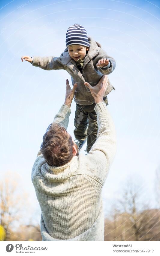 Vater wirft glücklichen Jungen in die Luft unter blauem Himmel Glück glücklich sein glücklichsein Park Parkanlagen Parks werfen Wurf Papas Väter Vati Vatis